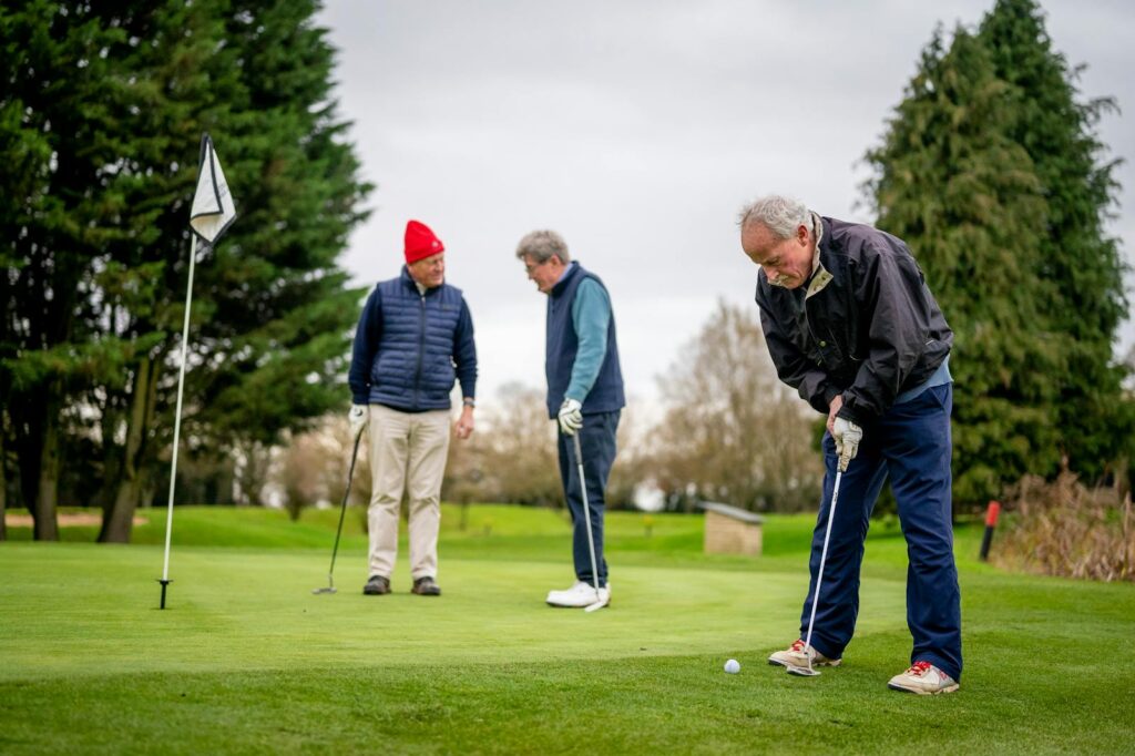 Three senior men enjoying a day of golf on a lush green course.