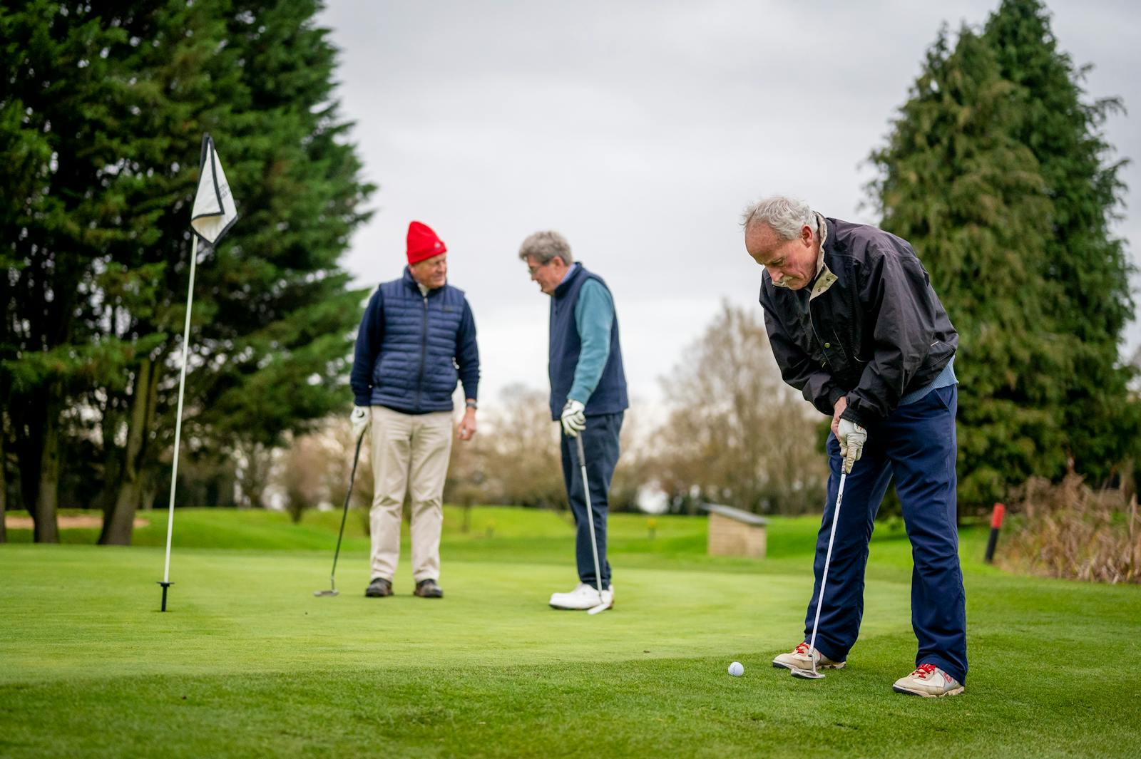 Three senior men enjoying a day of golf on a lush green course.
